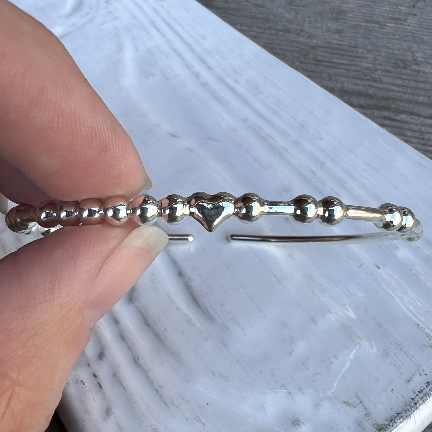 Woman holding a CUSTOM Couple Bracelet with 2 Names separated by a Heart