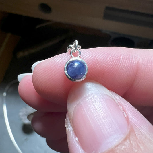 Woman holding the Blue Sapphire Birthstone Pendant with Silver Necklace